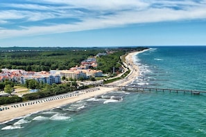 Una località costiera con una spiaggia, un molo e edifici con tetti rossi.
