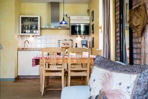 A kitchen with a dining table, chairs, a cabinet, and a hanging light fixture. - Holiday apartment with 1 bedroom (Kühlungsborn)