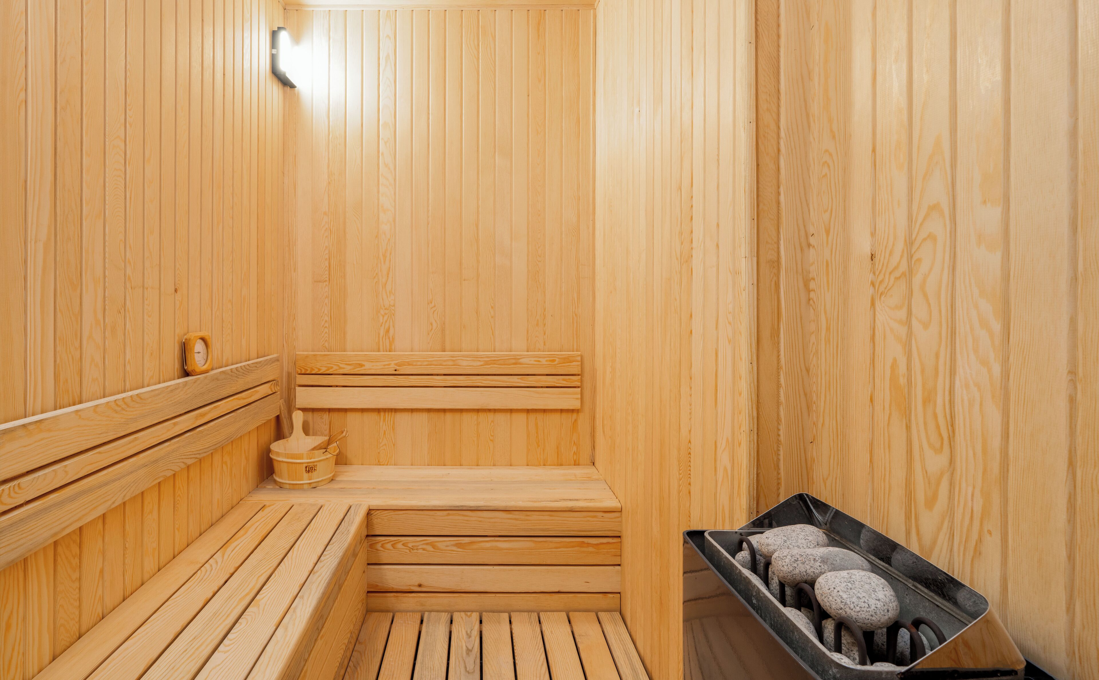 A wooden sauna with benches and a stone tray.