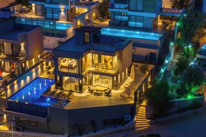 A modern multi-story residential building with a rooftop pool, outdoor seating areas, and a staircase leading to the upper levels. - Walk Distance to the Town (Kaş)