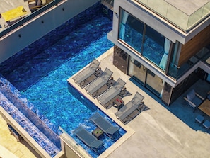 An aerial view of a modern hotel with a rooftop infinity pool, outdoor seating, and a glass-enclosed building. - Walk Distance to the Town (Kaş)