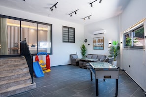 A modern living room with a glass table, a sofa, and a play area with a slide. - Walk Distance to the Town (Kaş)