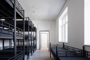 Un dormitorio con literas, una ventana y una puerta que da a otra habitación.