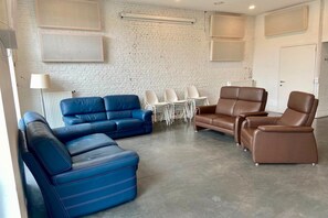 A room with a blue sofa, a brown leather chair, and a white brick wall.