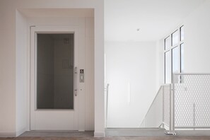 Una puerta blanca con picaporte, un panel de vidrio y señal de accesibilidad para sillas de ruedas.