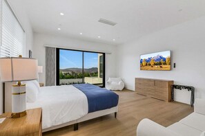 Une chambre d’hôtel moderne avec un grand lit, une télévision et une vue sur les montagnes.