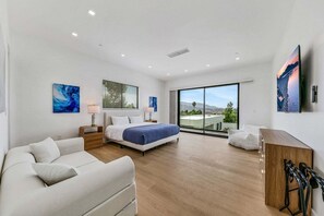 Un dormitorio moderno con una cama grande, un sofá, un escritorio con una silla y un televisor.