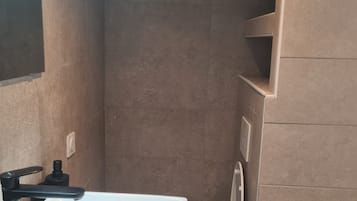 Et badeværelse med hvid vask, toilet og bruseområde.