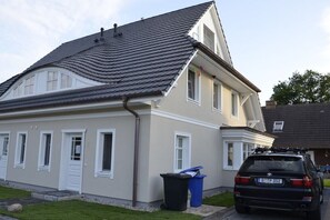 A two-story house with a sloped roof, a garage, and a parked car. - Holiday home in Zingst with sauna (Zingst)
