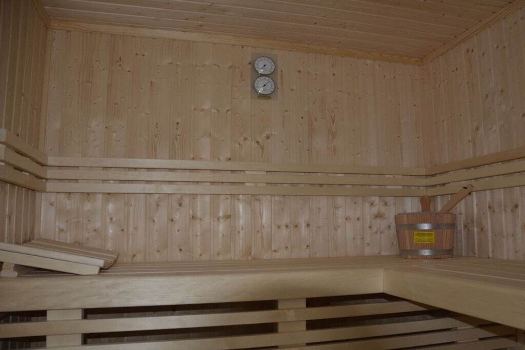 Una sala de sauna con paredes de madera, un banco y un balde de madera.