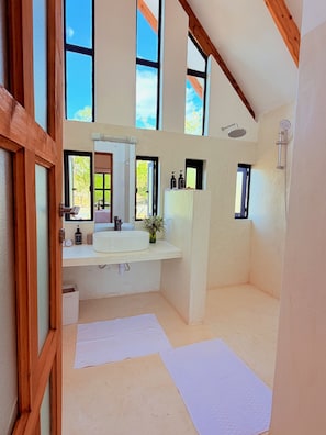 A modern bathroom with a large window, a built-in sink, and a shower.