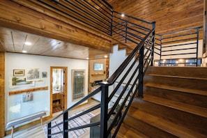 A wooden staircase with metal railings leading to an upper floor.
