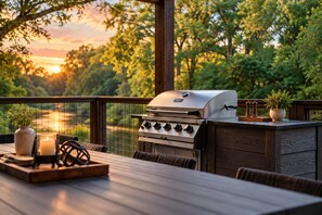A barbecue grill with a view of a sunset and trees.