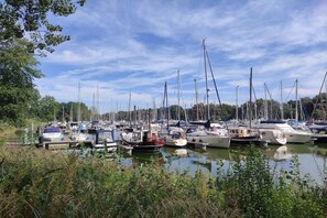 Ein Yachthafen mit mehreren Booten, die in ruhigem Wasser liegen, umgeben von viel Grün.