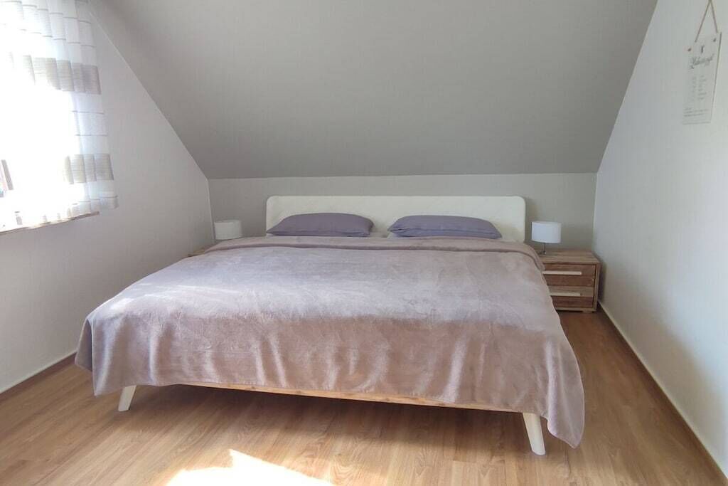 Une chambre à coucher avec un lit, deux tables de chevet et une fenêtre avec des stores.