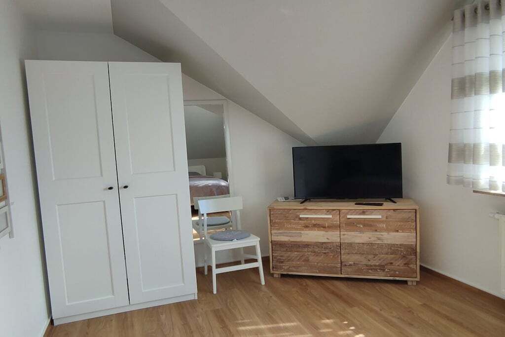Een slaapkamer met een kledingkast, een televisie, een bed en een stoel.