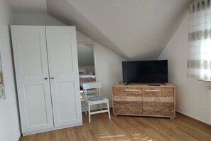 Ein Schlafzimmer mit Kleiderschrank, Fernseher, Bett und Stuhl.