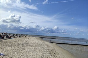 A beach with a sandy shore, a few people, and a clear sky. - Holiday home with 1 bedroom (Wangerland)