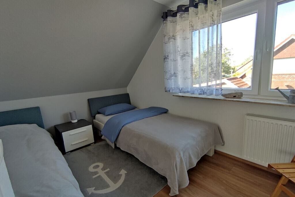 Une chambre avec deux lits, une fenêtre avec des rideaux, un radiateur et une petite table.