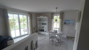 Um quarto com uma mesa de jantar, cadeiras, um armário branco e uma janela com cortinas.