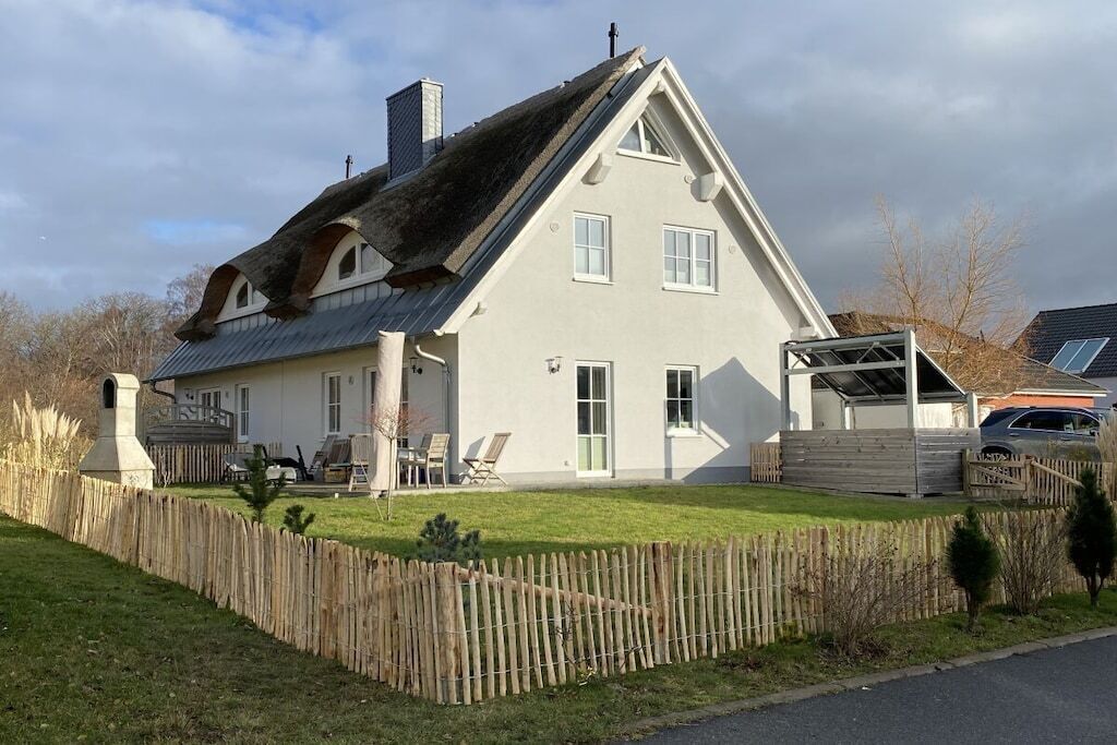 Ein zweigeschossiges Haus mit einem geneigten Dach, einem umzäunten Garten und einer Garage.