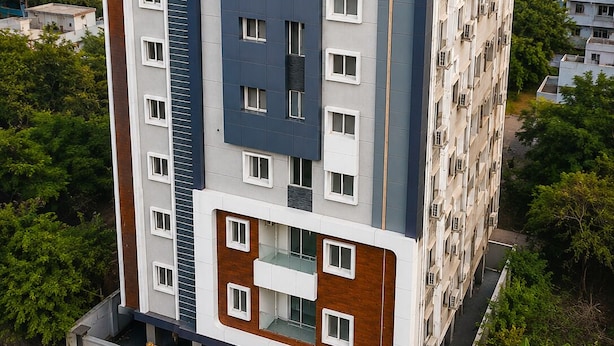 Ein mehrgeschossiges Wohngebäude mit modernem Design, das Balkone und verschiedene Fensterformen aufweist.