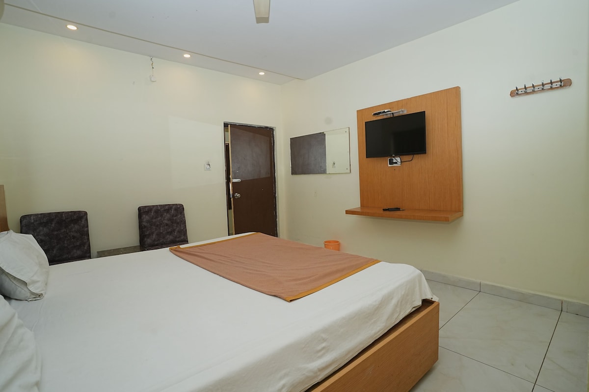Een slaapkamer met een bed, een aan de muur bevestigde televisie en een deur.