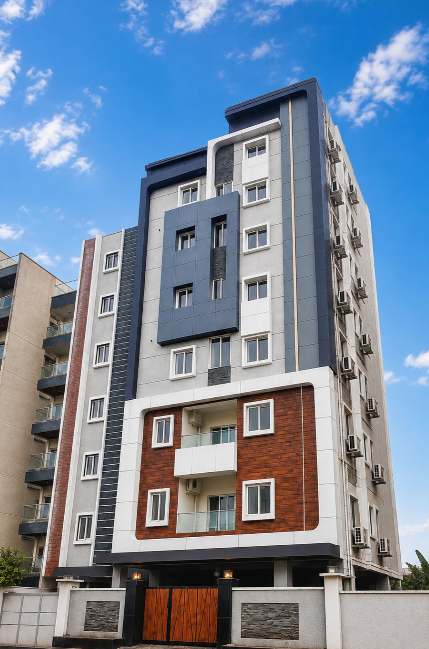 Un edificio residencial de varios pisos con un diseño arquitectónico moderno, que combina fachadas de ladrillo y concreto, y una entrada central destacada con una puerta de madera.