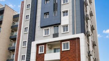 Un edificio residencial de varios pisos con un diseño arquitectónico moderno, que combina fachadas de ladrillo y concreto, y una entrada central destacada con una puerta de madera.