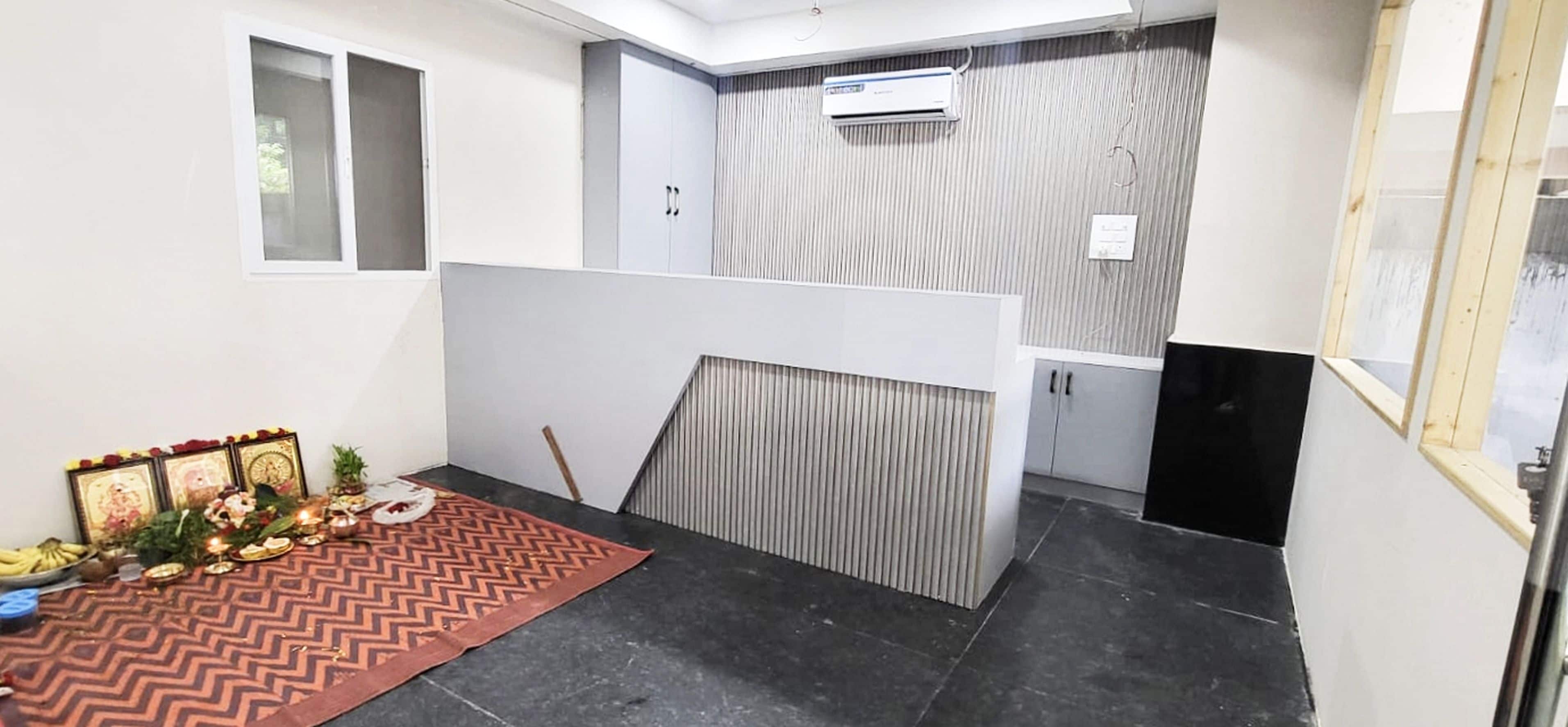 Una habitación con piso de baldosas negras, un separador blanco y un ventanal pequeño.