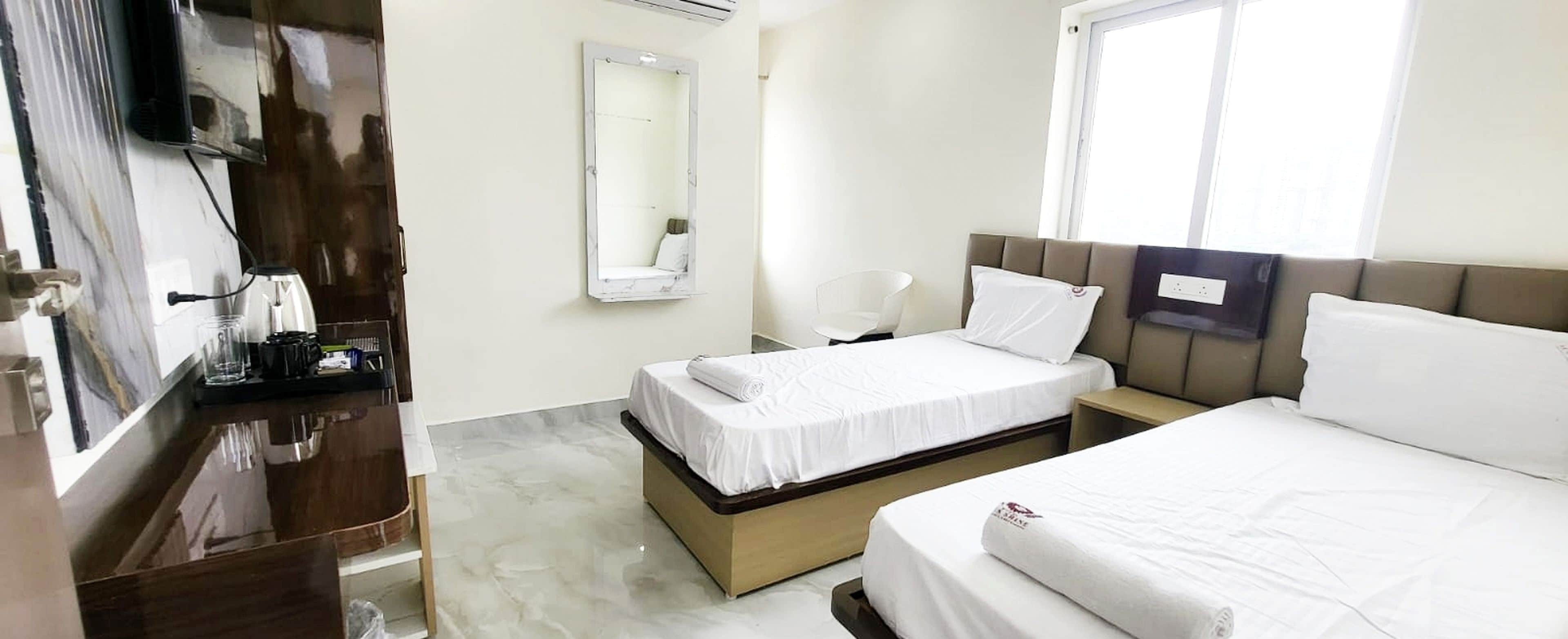 Habitación de hotel con dos camas, un espejo, un televisor y una mesita con artículos de aseo.