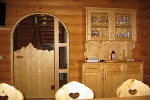 A wooden cabin interior with a glass door leading to a staircase, a cabinet with glass doors, and heart-shaped cutouts on the wall. - Holiday apartment with 2 bedrooms (Heiligenblut)
