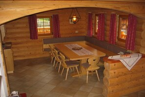 Ein Holzblockhaus-Interieur mit einem Holzesstisch, Stühlen und einer Bank.