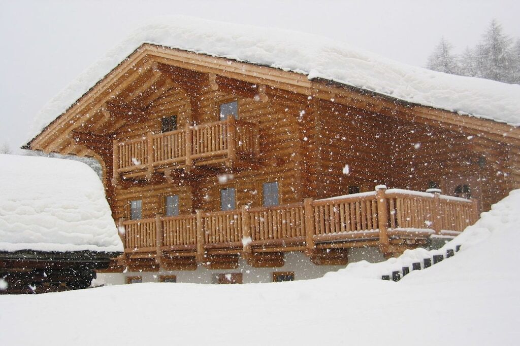 Una cabaña de madera con balcón, rodeada de nieve.