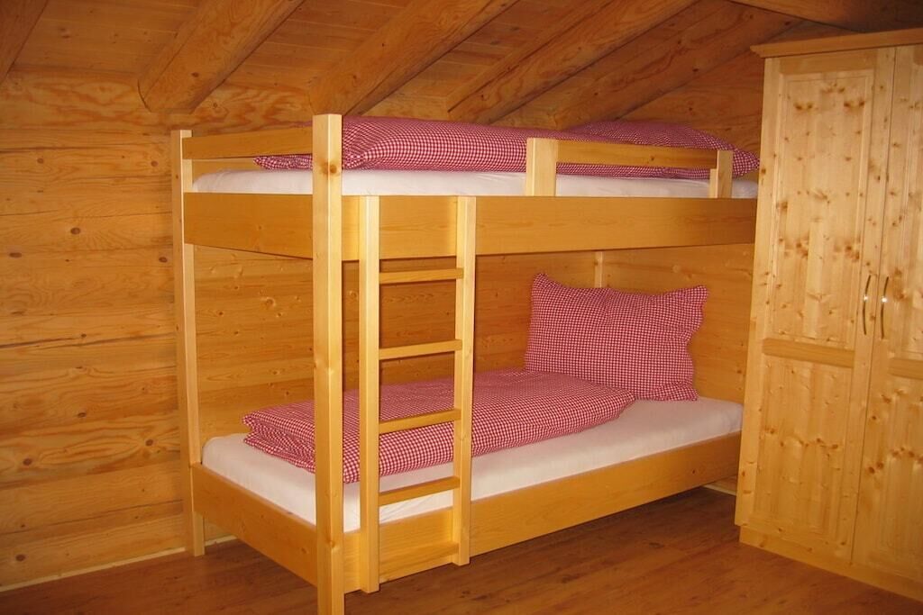 Un letto a castello con una scala, pareti in legno e un armadio.