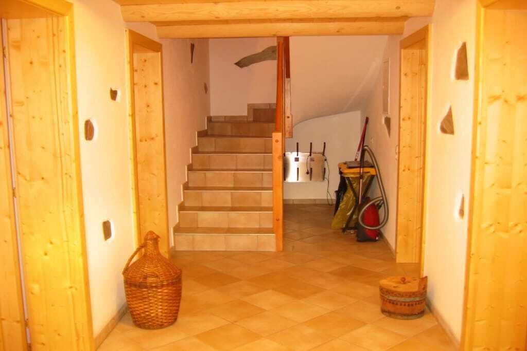 A wooden staircase leading to a room with a tiled floor, a basket, and a small stool.