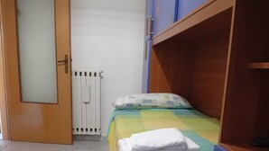 Un dormitori amb llit, radiador, armari de fusta i porta.