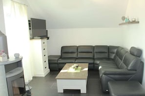 A modern living room with a sectional sofa, a coffee table, a flat-screen TV, and a fireplace. - Holiday apartment with 2 bedrooms (Wendisch Rietz)