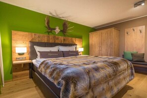 Una camera da letto con un letto grande, una testiera in legno, pareti verdi e un ornamento decorativo a forma di corno di cervo.