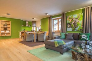 A living room with a sofa, a glass coffee table, and a painting of a moose. - Holiday apartment in Oberstdorf with Wi-Fi (Oberstdorf)