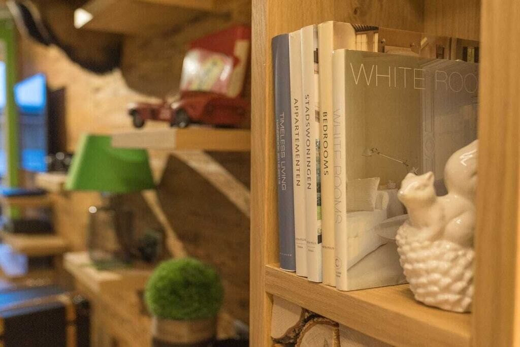 A bookshelf with books and a white ceramic cat figurine.