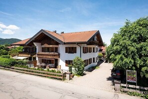 Un edificio a due piani con tetto spiovente, un balcone e un vialetto lastricato.