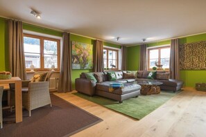 A furnished living room with a sofa set, a dining table with chairs, and a large window with curtains. - Holiday apartment in Oberstdorf with Wi-Fi (Oberstdorf)