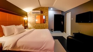 Habitació d'hotel amb un llit, una televisió i una paret de pedra.