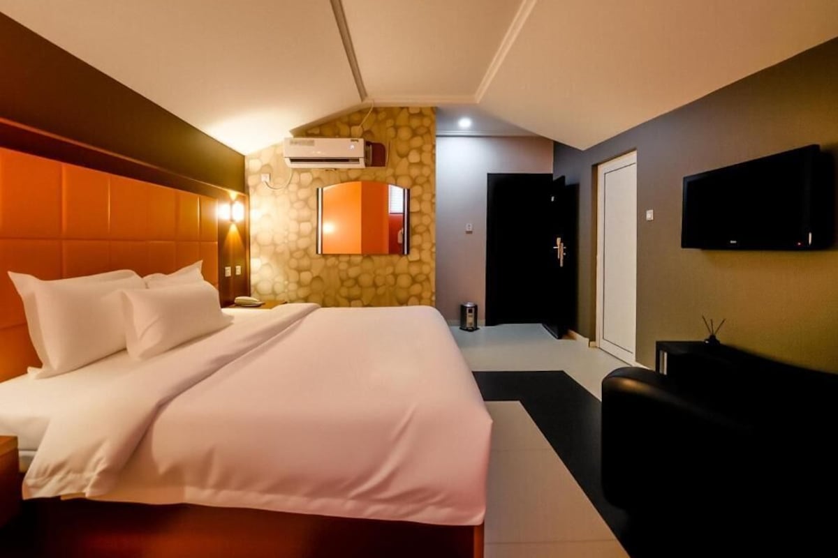 Een hotelkamer met een bed, een televisie en een stenen muur.