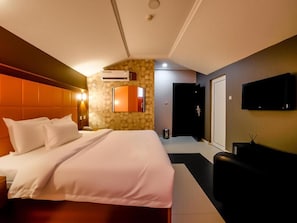 Een hotelkamer met een bed, een televisie en een stenen muur.