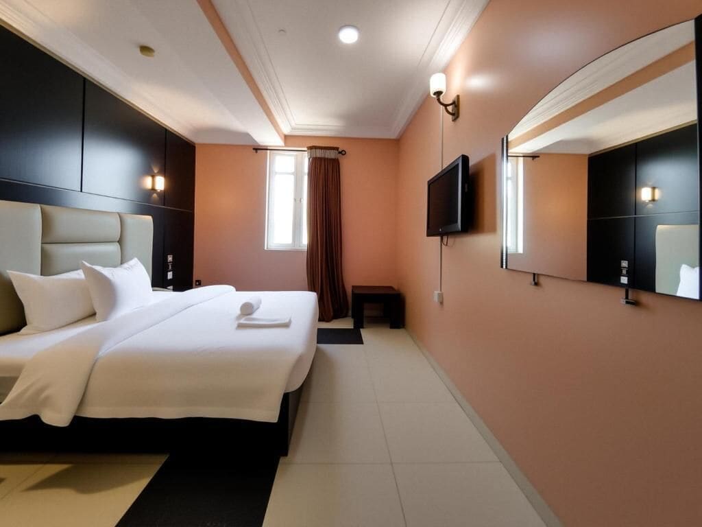 Een hotelkamer met een groot bed, een flatscreen televisie en een spiegel aan de muur.