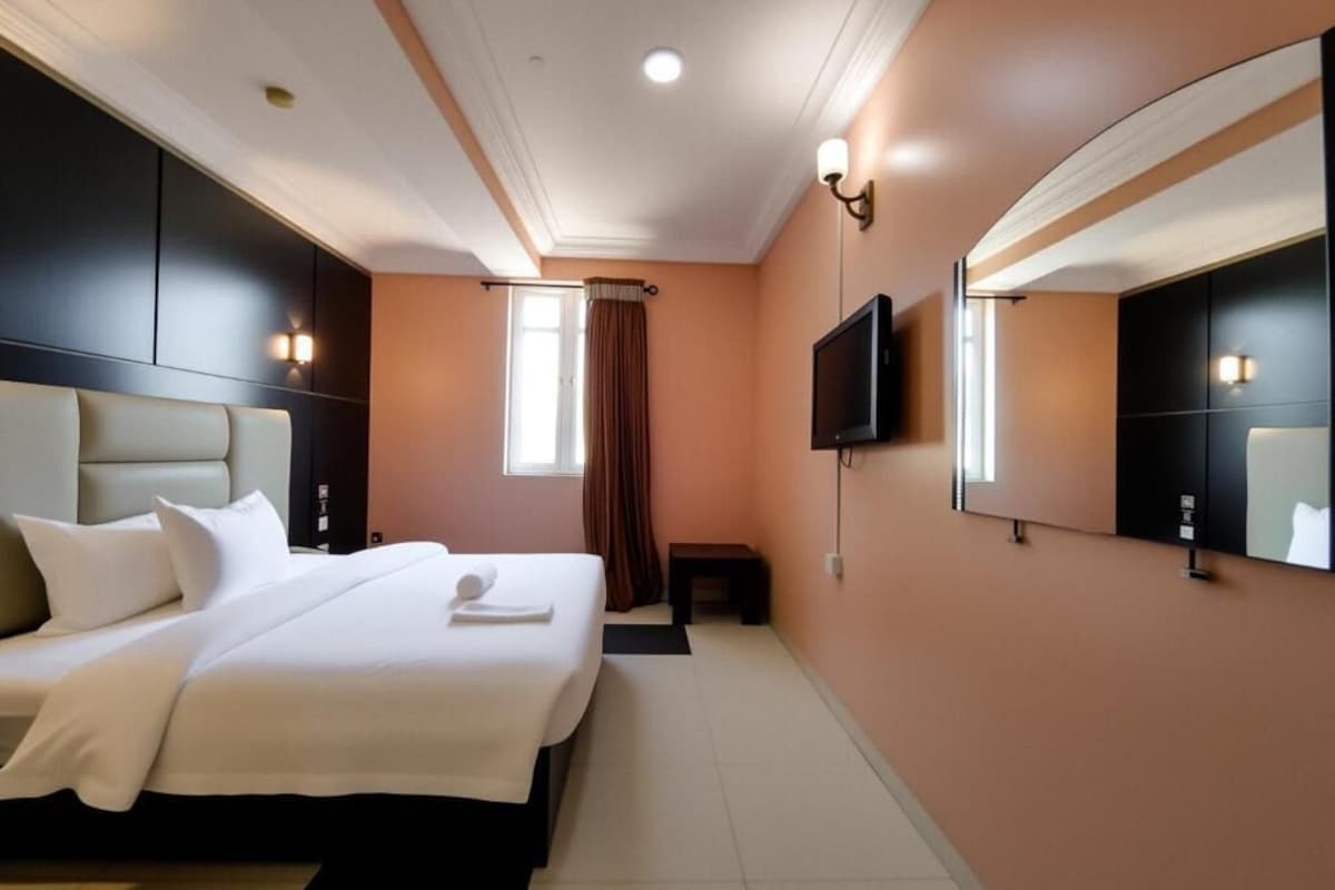 Een hotelkamer met een groot bed, een flatscreen televisie en een spiegel aan de muur.