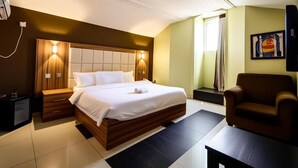 Habitació d'hotel amb un llit, taules de nit, una cadira i un quadre a la paret.