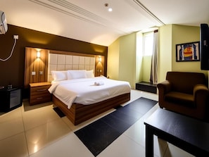 Een hotelkamer met een bed, nachtkastjes, een stoel en een schilderij aan de muur.